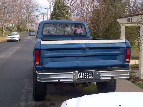 1978 Ford Bronco - A blue pickup truck is parked on the side of the road with a 'For Sale' sign in the rear window.
