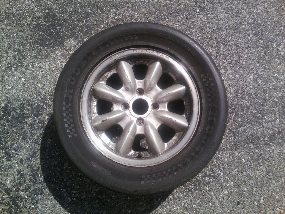 old alloy wheel with a tire on asphalt