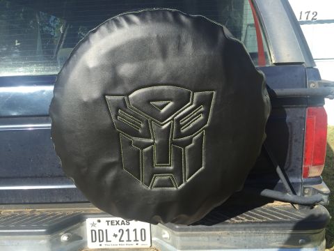 1993 Ford Bronco - A black spare tire cover with the iconic Transformers logo is mounted on the rear of an SUV.