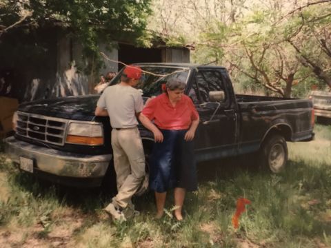 1993 Ford Bronco - A black 1992 Ford F-150 pickup truck is parked outside a rustic building with two people standing nearby.