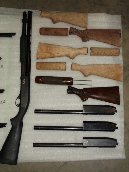 1995 Mercury Grand Marquis - Various shotgun components, including a receiver, barrels, and multiple stock and forend pieces, are arranged on a white surface.