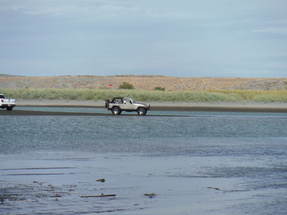 White Jeep Wrangler driving through shallow water, side view