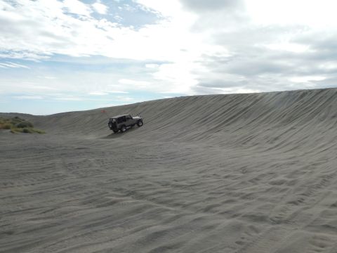 2005 Jeep Wrangler - A Jeep Wrangler navigates a steep sand dune on a cloudy day.