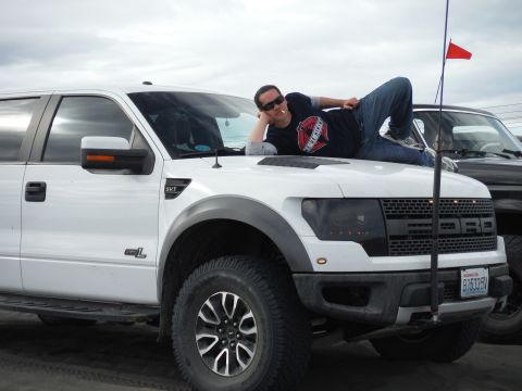 2005 Jeep Wrangler - A man poses on the hood of a white Ford F-150 SVT Raptor, with another vehicle visible behind it.