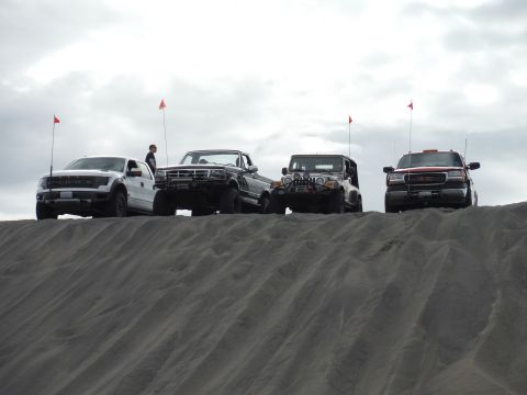 2005 Jeep Wrangler - Four off-road vehicles, including a 2005 Jeep Wrangler, are positioned on a sand dune.
