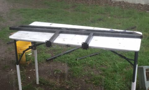 1993 Ford Bronco - Metal sliders are placed on a folding table outside, with a yellow bucket visible to the left.