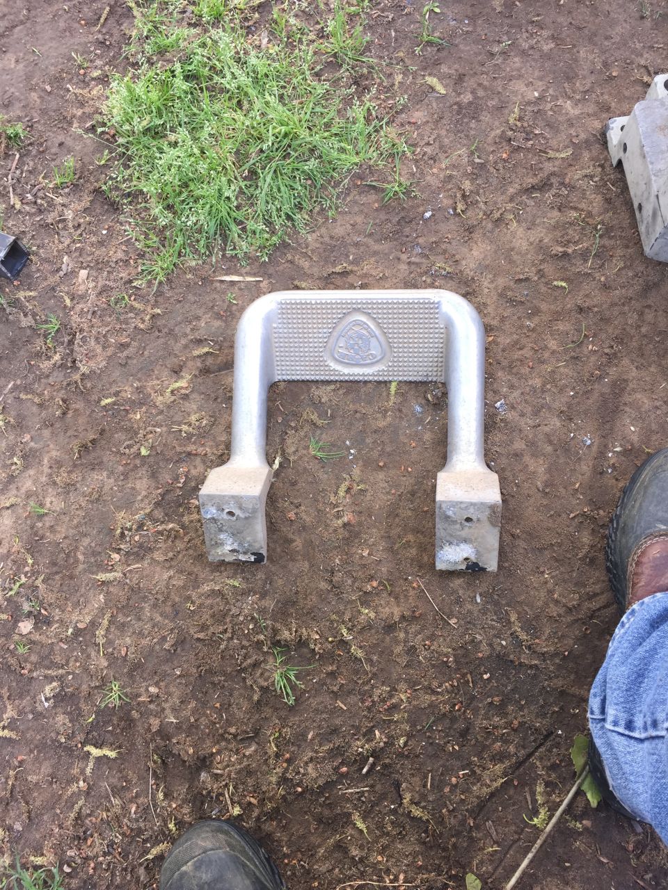 Metal step slider with a triangular emblem on top, lying on the ground