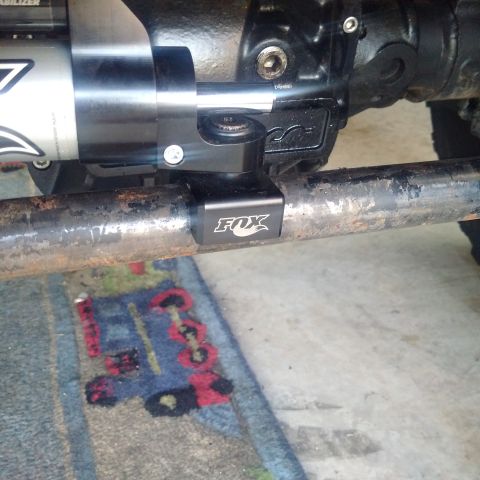 1978 Ford Bronco - Fox shock absorber mount attached to a metal bar, likely part of a vehicle's suspension system.