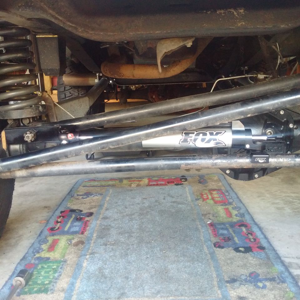 Underside of a vehicle showing a Fox shock absorber and suspension linkages