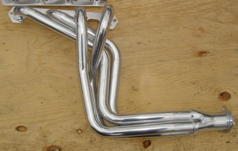 1986 Ford Bronco - A set of shiny chrome exhaust headers are shown mounted on a wooden surface.