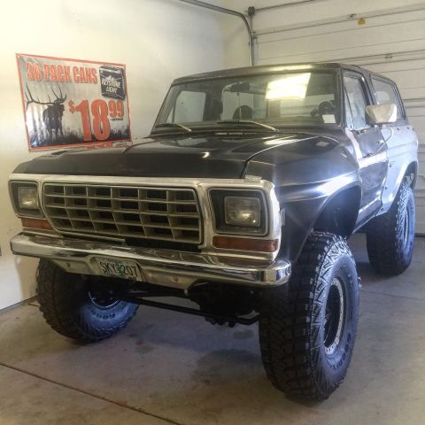 1979 Ford Bronco - A black 1979 Ford Bronco with aftermarket wheels and tires is parked in a garage. A sign for Keystone Light beer is visible on the wall beh…