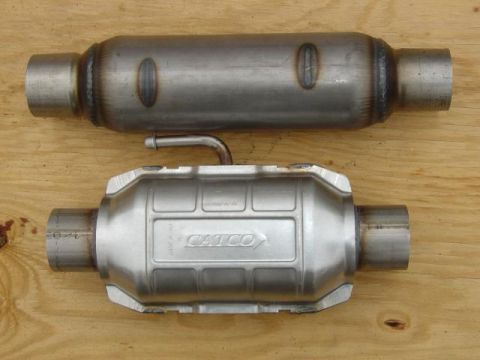 1986 Ford Bronco - Two exhaust system parts, one a catalytic converter with the CATCO brand visible, are laid out on a wooden surface.