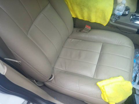 2000 Mercury Grand Marquis - The interior of a car features tan leather seats, a yellow towel, and a water bottle on the center console.