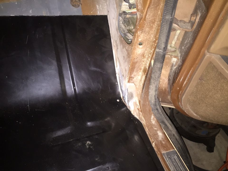 Interior of a vehicle showing the floor pan and door jamb.