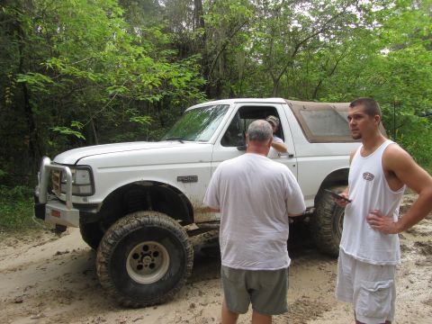 1995 Ford Bronco - A white Ford Bronco with a brush guard is parked on a dirt path surrounded by trees. Three men are standing around the vehicle, two in the…