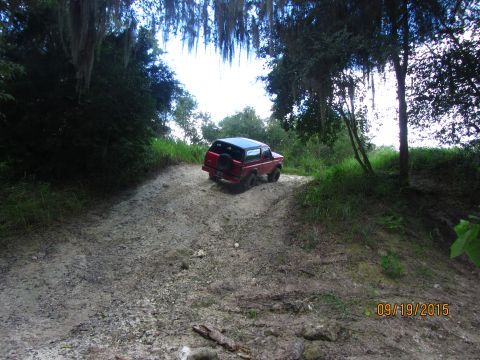 1995 Ford Bronco - A red Ford Bronco is driving up a muddy, off-road trail surrounded by trees and vegetation. The date "09/19/2015" is visible in the lower r…