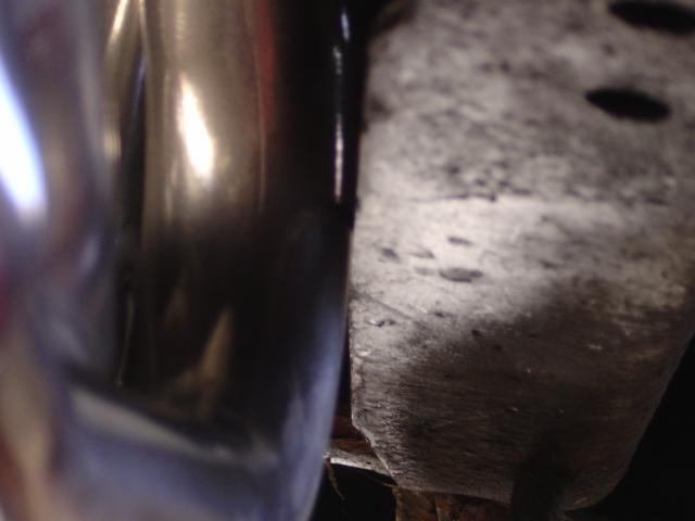 Close-up of chrome tubing beside a cast metal bracket with holes under a Ford Bronco