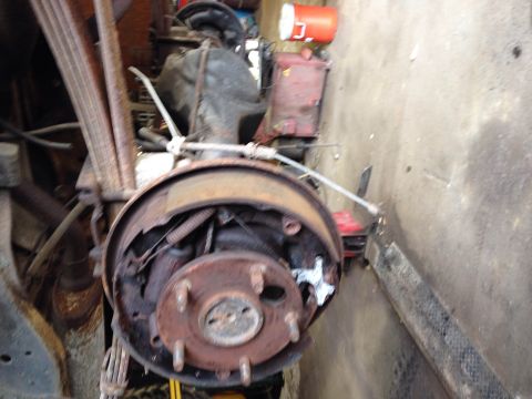 1979 Ford Bronco - A close-up view of a rusty drum brake assembly and leaf springs on what appears to be a vintage truck or SUV. The brake drum is partially r…