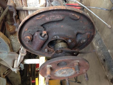 1979 Ford Bronco - A heavily rusted drum brake assembly is shown, with the drum removed to reveal the brake shoes and wheel cylinder. The hub and studs are vi…