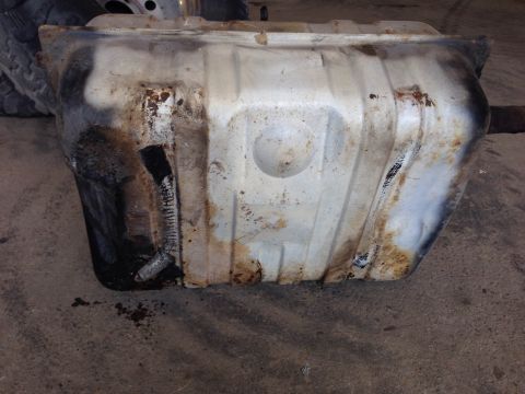 1979 Ford Bronco - A rusty, dented, and discolored metal fuel tank is shown resting on a concrete surface. The tank appears to be from an older vehicle, with…