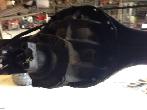 1979 Ford Bronco - A close-up view of a black differential housing and U-joint assembly, likely from a vintage Ford Bronco, in a workshop setting.