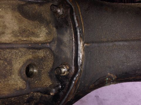 1979 Ford Bronco - A close-up view of a heavily greased and dirty metal differential housing with visible weld seams and threaded bolt holes. The housing appe…