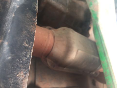 1993 Ford Bronco - The underside of a vehicle shows a catalytic converter connected to an exhaust pipe. The vehicle appears to be a truck or SUV with a black…