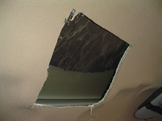 Torn beige headliner with dark material visible underneath