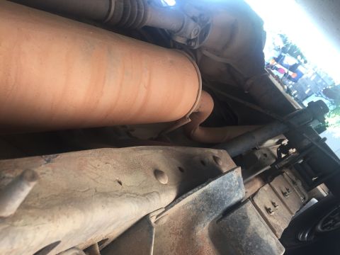1993 Ford Bronco - The underside of a vehicle shows a large exhaust muffler and part of the drivetrain, including a driveshaft and differential. The frame and…
