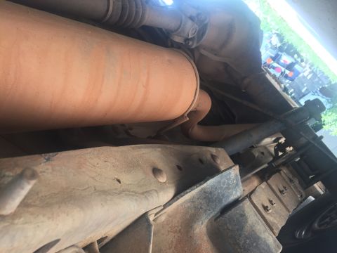 1993 Ford Bronco - The underside of a vehicle shows the exhaust system, including a large muffler, and part of the drivetrain. The frame and suspension compon…