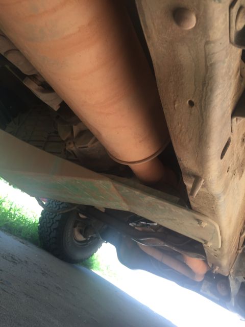 1993 Ford Bronco - Underside view of a 1993 Ford Bronco showing the exhaust system, transmission, and frame rails. A large, orange-brown muffler is prominentl…