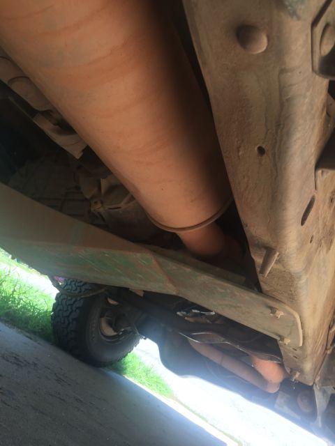 1993 Ford Bronco - Underside view of a 1993 Ford Bronco, showing the exhaust system, frame, and a portion of the rear tire. The vehicle appears to be covered…