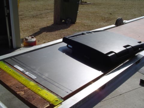 1999 Ford Taurus - A black plastic automotive part is shown with a yellow ruler and a metal sheet on a workbench.