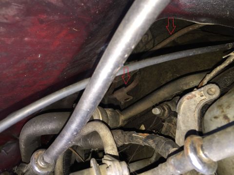 1989 Ford Bronco - This image shows a close-up view of the engine bay of a vehicle, focusing on various hoses, metal lines, and mounting brackets. Two red arr…