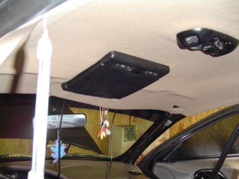 1999 Ford Taurus - Interior view of a vehicle's headliner, showing an overhead console and a rear-seat entertainment screen.