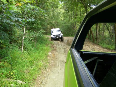 1986 Ford Bronco - A lime green vehicle is parked on a muddy, wooded trail, with a white Jeep visible further up the path.