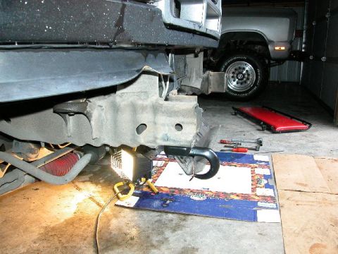 1995 Ford Bronco - A close-up of a vehicle's front recovery hook and frame, with another truck visible in the garage.