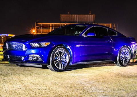 2015 Ford Mustang - A blue 2015 Ford Mustang coupe is parked outdoors at night with city lights in the background.