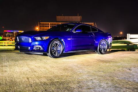 2015 Ford Mustang - A blue 2015 Ford Mustang coupe is parked outdoors at night, showing its front and side profile.