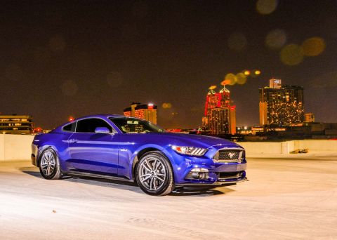 2015 Ford Mustang - A blue 2015 Ford Mustang is parked on a rooftop with a city skyline illuminated at night.
