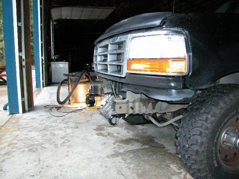 1995 Ford Bronco - The front of a truck is shown with its bumper removed, revealing the frame and tow hook underneath.
