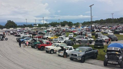 1995 Ford Bronco - A large outdoor gathering of trucks and SUVs under a cloudy sky.