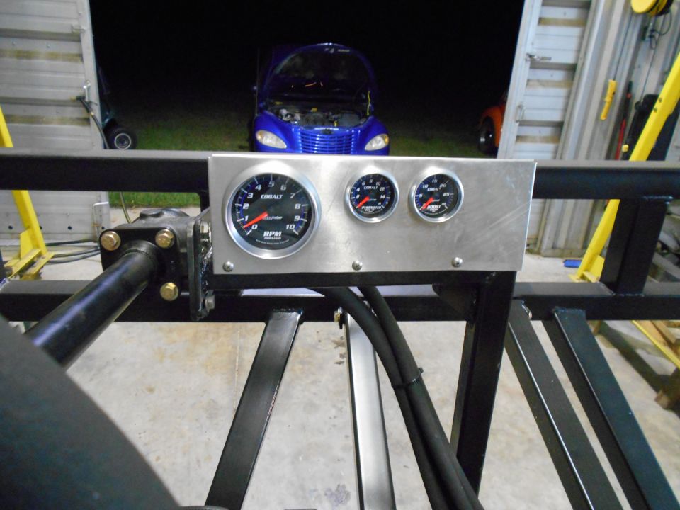 Custom gauge panel with tachometer, oil pressure, and water temperature gauges. Blue car in background