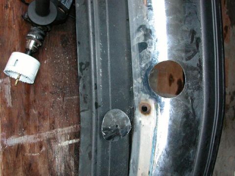 1995 Ford Bronco - A drill and hole saw are positioned near a chrome bumper that has been modified with new holes.