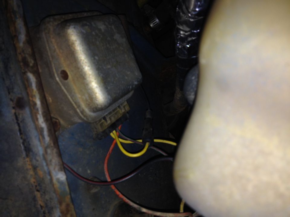 Close-up of a metal voltage regulator with yellow and red wires connected