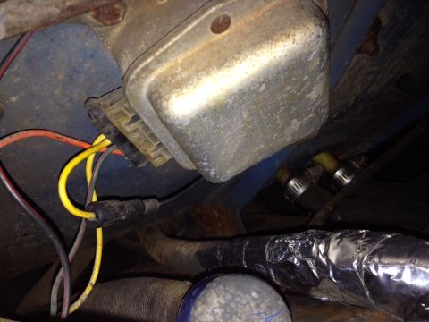 1973 Ford Bronco - Close-up view of a vehicle's electrical system, focusing on a voltage regulator and its wiring harness.