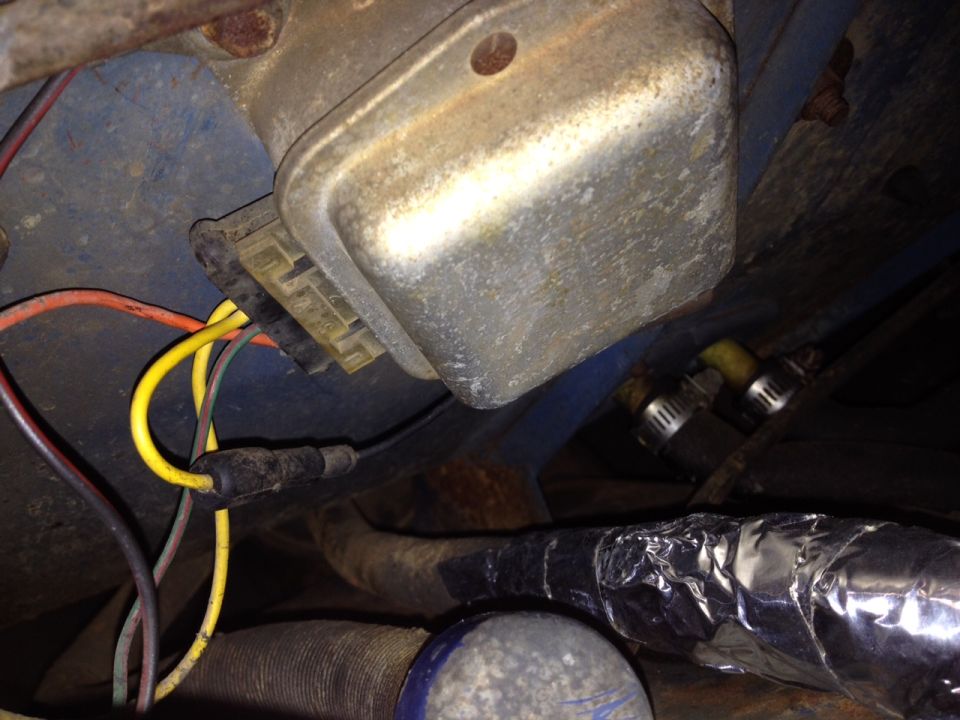 Metal voltage regulator with yellow and red wires connected, mounted on blue painted surface