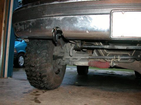 1995 Ford Bronco - The rear of a vehicle is shown, focusing on the bumper and suspension system, with another vehicle in the background.