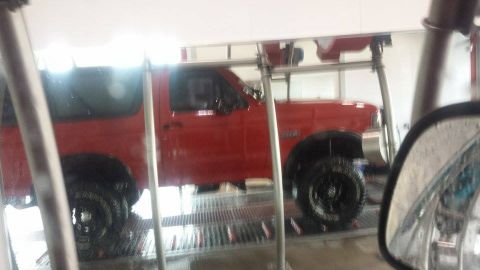 1995 Ford Bronco - A red 1995 Ford Bronco is seen from the side while being washed at an automated car wash.