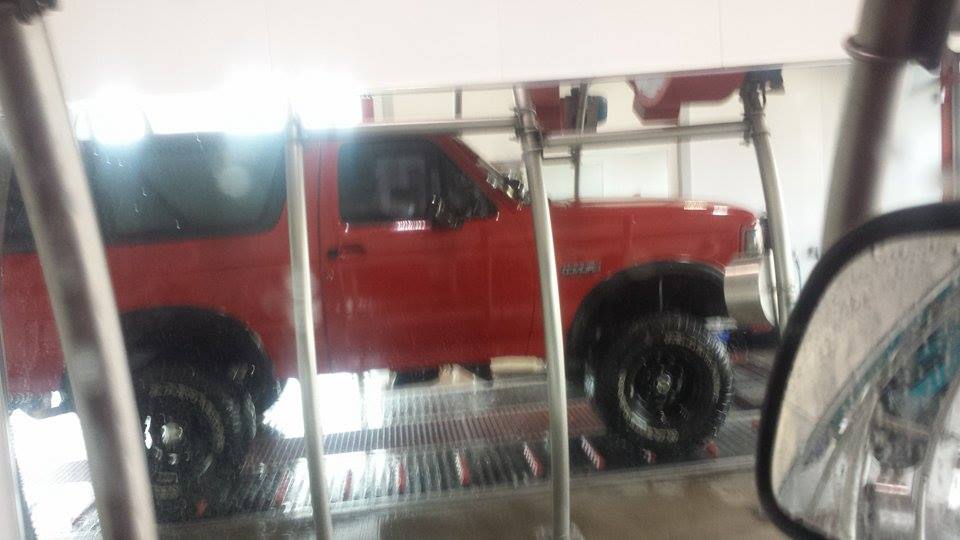 Side view of a red 1995 Ford Bronco at a car wash